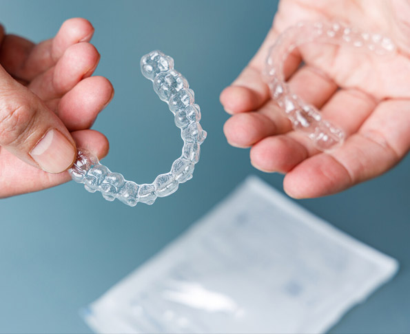 Holding two clear dental aligners | Clear Aligners at 208 Dental