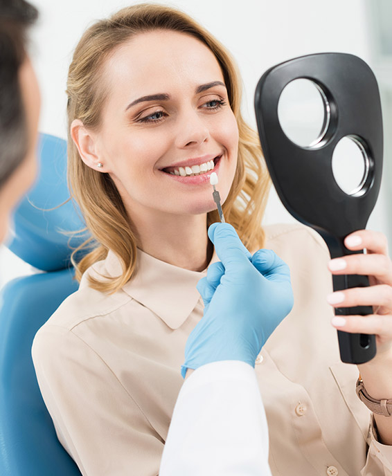 a lady woman is smiling while fronting a mirror after dental implants 